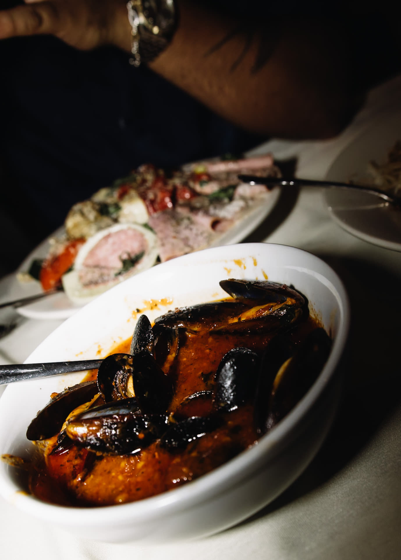 A bowl of mussels in red sauce being served at the table