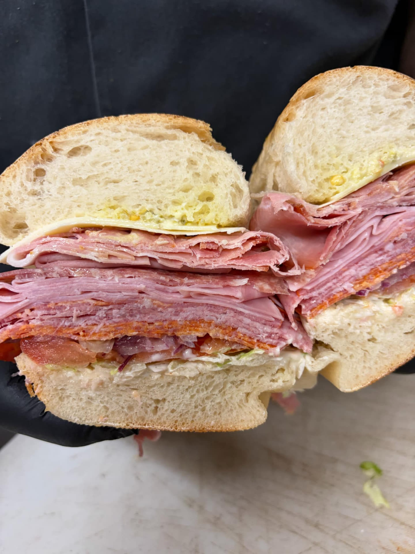 A stacked Italian sub cut in half on a counter