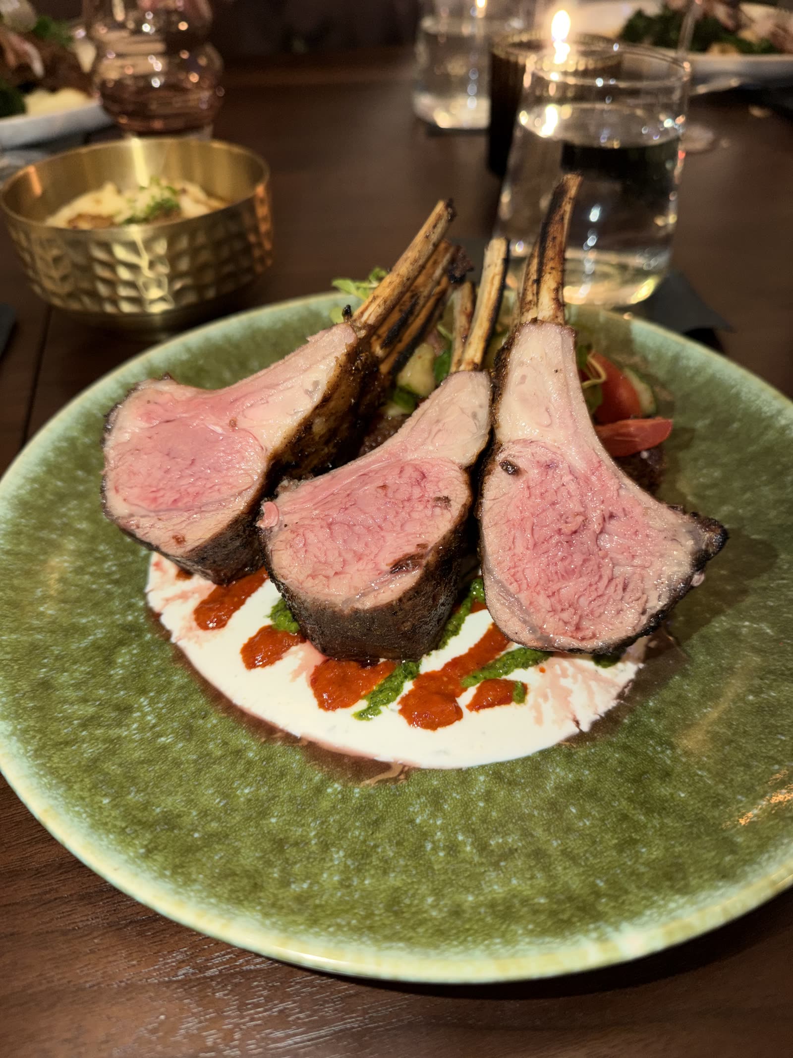 A rack of lamb chops plated on a green ceramic dish